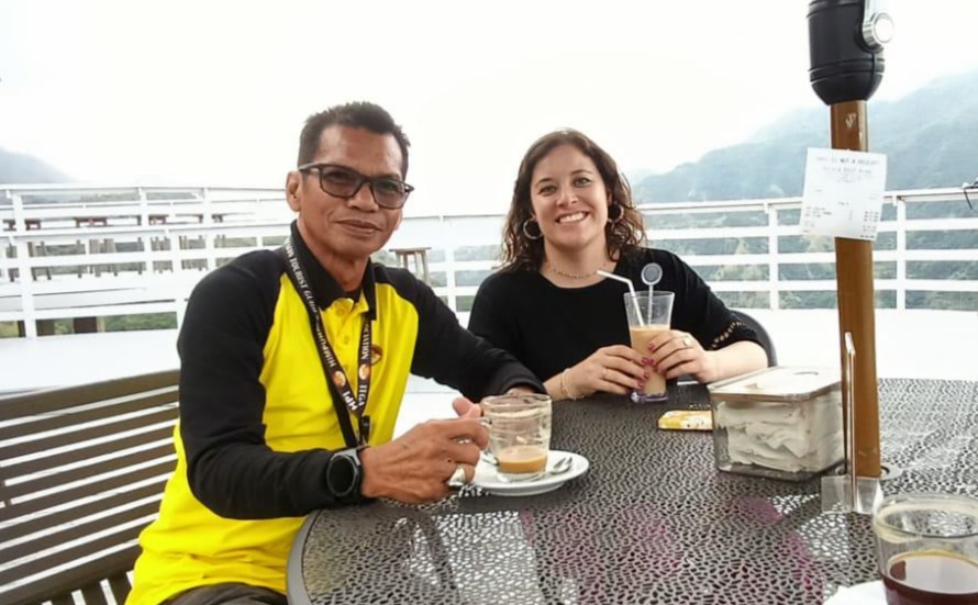 Author with local guide Salim at a café in Sulawesi, Indonesia, with the Erotic Mountain visible in the misty background