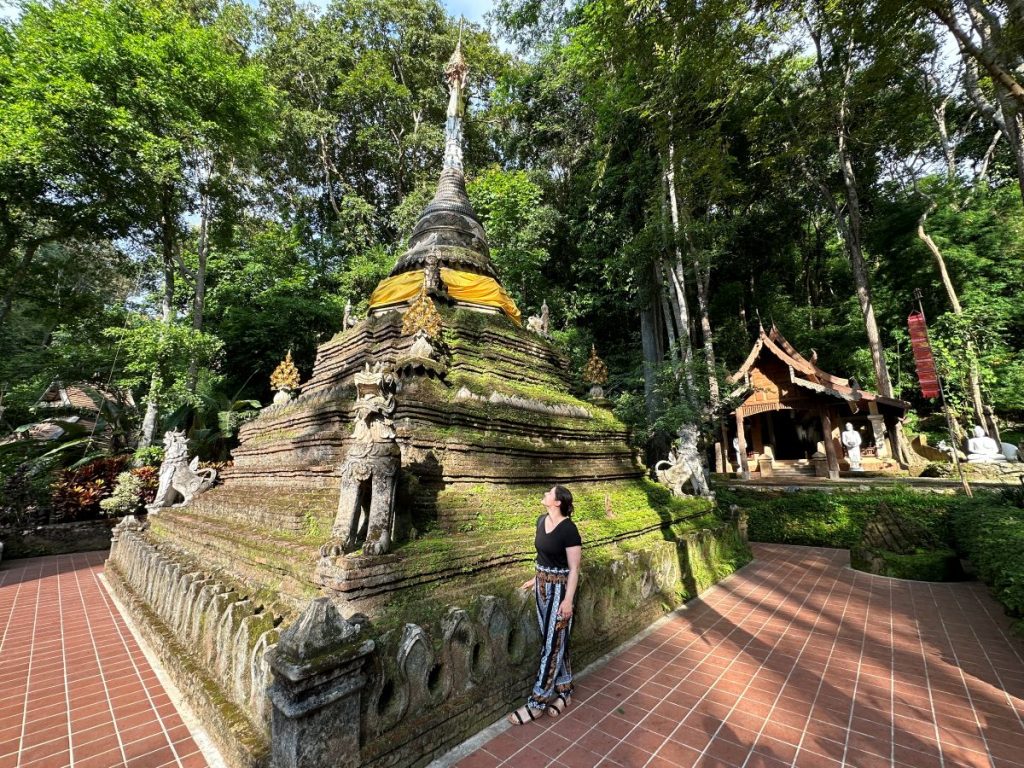 The author standing next to an ancient, moss-covered stone chedi at Wat Pha Lat forest temple in Chiang Mai, Thailand.